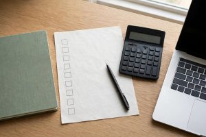 Notebook, calculator and laptop with a checklist for checking a money website